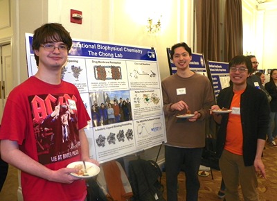 People posing next to poster displays