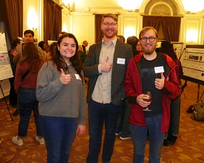 Three people pose with a thumbs up