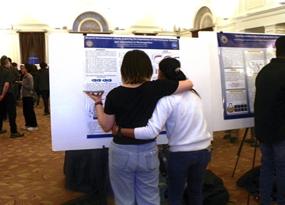 Two people hugging in front of a poster display