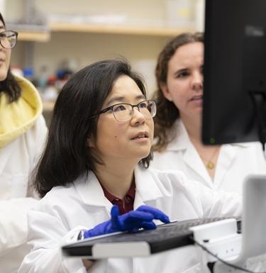 Three scientists gather around a computer