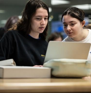 Two students work at the same laptop
